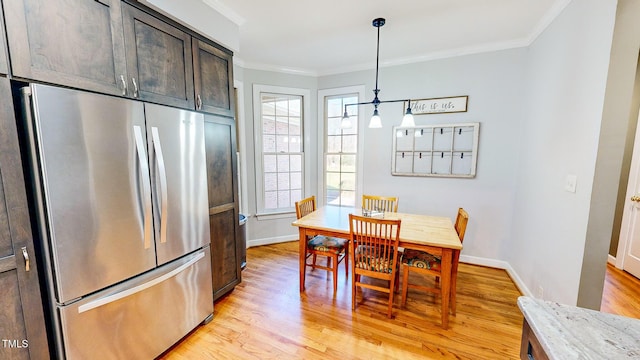 dining room with crown molding, plenty of natural light, and light hardwood / wood-style floors