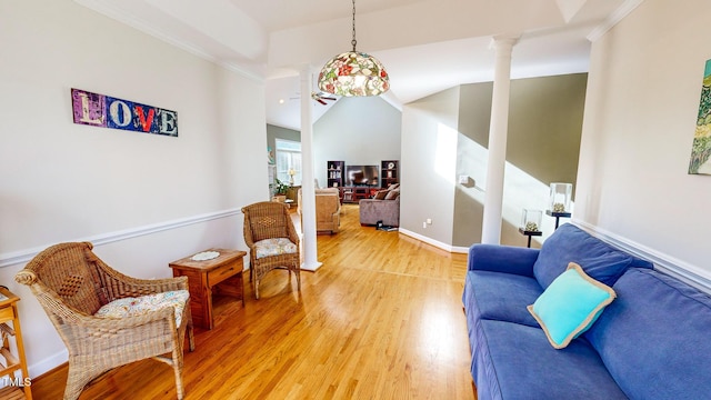 living area with hardwood / wood-style flooring, crown molding, vaulted ceiling, and ornate columns