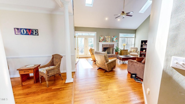 living room featuring a brick fireplace, light hardwood / wood-style flooring, and decorative columns