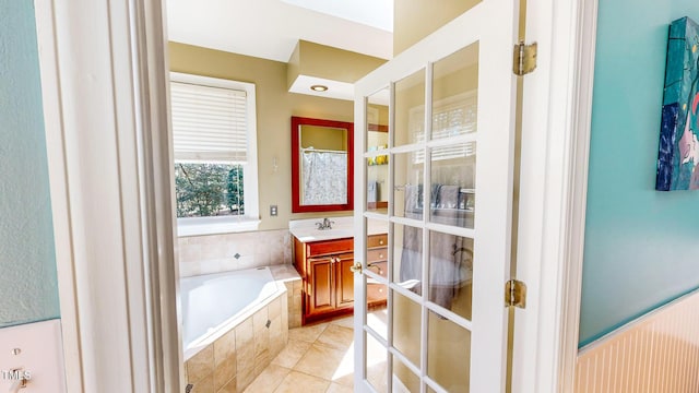 bathroom with french doors, vanity, a relaxing tiled tub, and tile patterned flooring