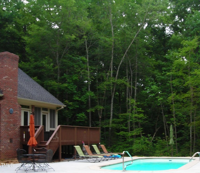 view of swimming pool featuring a deck and a patio