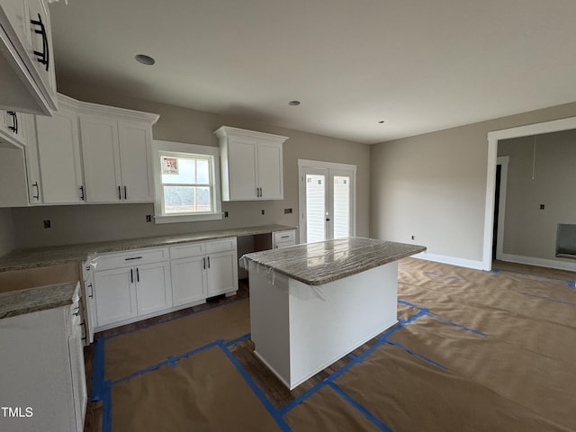 kitchen with french doors, a wealth of natural light, a kitchen island, and white cabinets