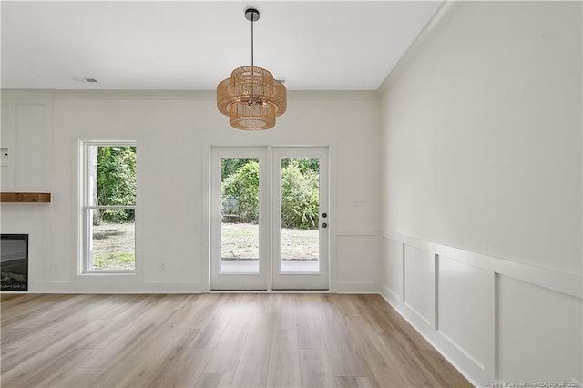 5210 Maxwell Rd, Stedman, NC 28391 - unfurnished dining area featuring a chandelier, healthy amount of natural light, light wood finished floors, a glass covered fireplace, and a decorative wall