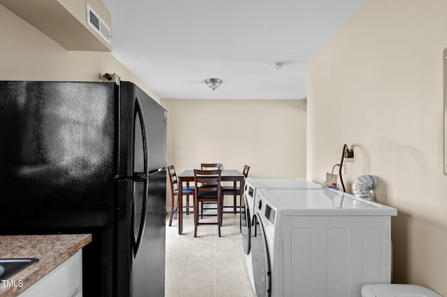 kitchen with separate washer and dryer, white cabinetry, and black fridge