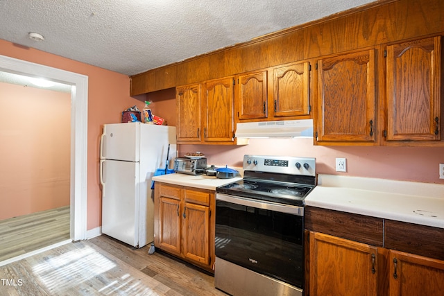 kitchen with light wood-type flooring, stainless steel range with electric cooktop, a textured ceiling, and white refrigerator