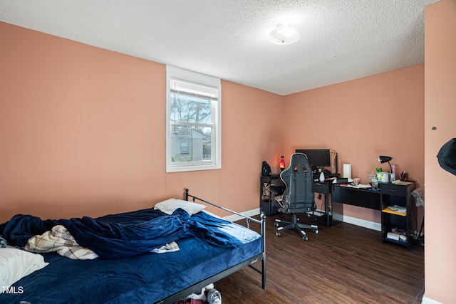 bedroom with a textured ceiling and dark hardwood / wood-style flooring