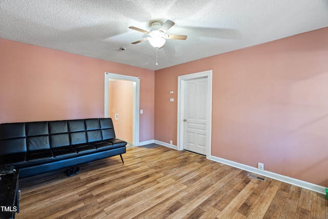 sitting room featuring ceiling fan, wood-type flooring, and a textured ceiling