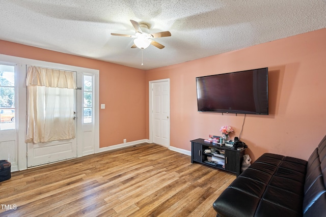 unfurnished living room featuring ceiling fan, plenty of natural light, a textured ceiling, and light hardwood / wood-style floors