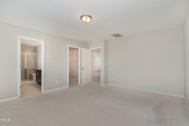 unfurnished bedroom featuring a spacious closet, visible vents, baseboards, light carpet, and a closet