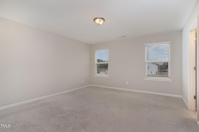 empty room with light carpet, visible vents, and baseboards