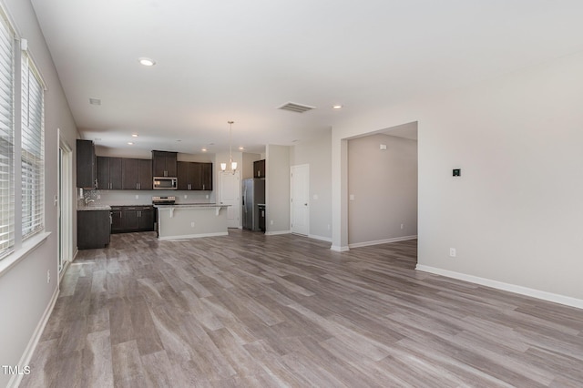 unfurnished living room featuring visible vents, baseboards, recessed lighting, light wood-style flooring, and a sink