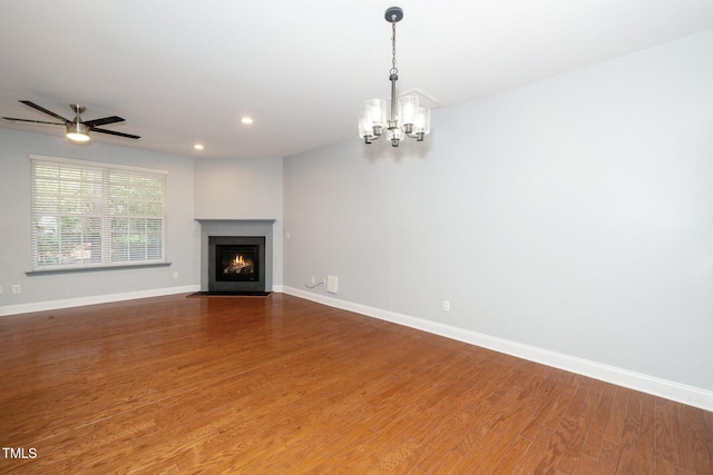 unfurnished living room featuring a chandelier, baseboards, wood finished floors, recessed lighting, and a fireplace with flush hearth