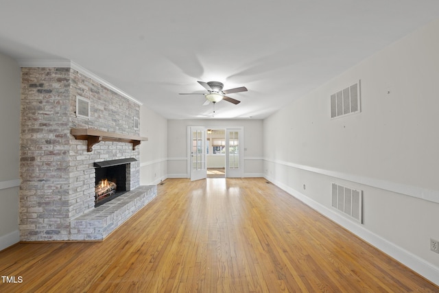 unfurnished living room featuring a fireplace, ceiling fan, and light wood-type flooring