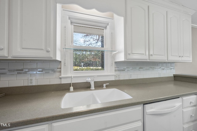 kitchen featuring white dishwasher, sink, tasteful backsplash, and white cabinets