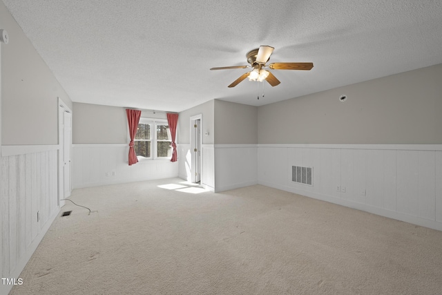 carpeted spare room featuring ceiling fan and a textured ceiling