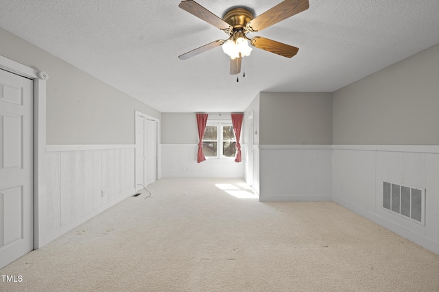 additional living space featuring ceiling fan, light colored carpet, and a textured ceiling