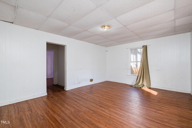 empty room featuring dark wood-type flooring and a paneled ceiling