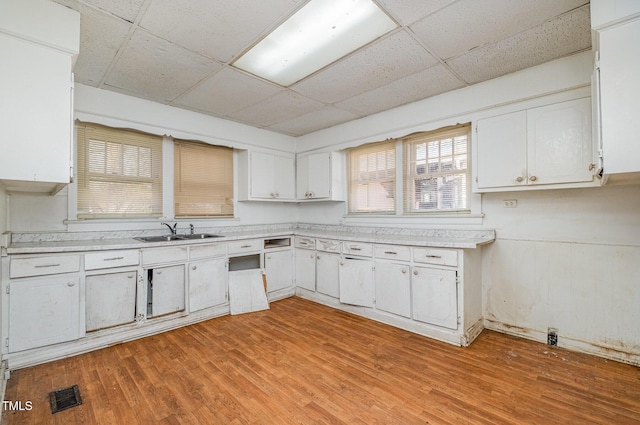 kitchen with white cabinetry, sink, a paneled ceiling, and light wood-type flooring