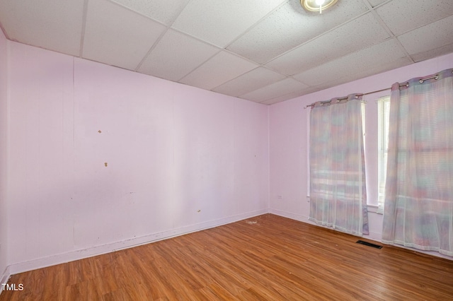 empty room with wood-type flooring and a drop ceiling