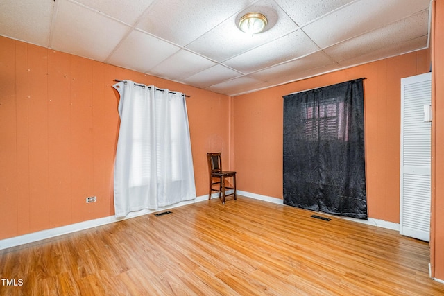 spare room with hardwood / wood-style flooring, a paneled ceiling, and wood walls