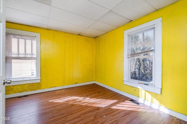 unfurnished room with plenty of natural light, wood-type flooring, and a paneled ceiling