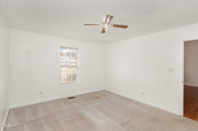 carpeted empty room featuring ceiling fan and a textured ceiling