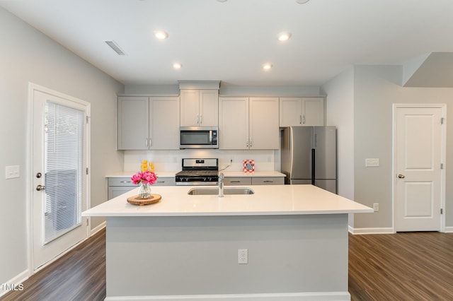 kitchen with stainless steel appliances, sink, a center island with sink, and dark hardwood / wood-style floors