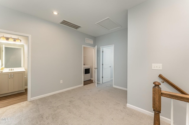 unfurnished bedroom featuring ensuite bathroom, washer / clothes dryer, sink, and light carpet