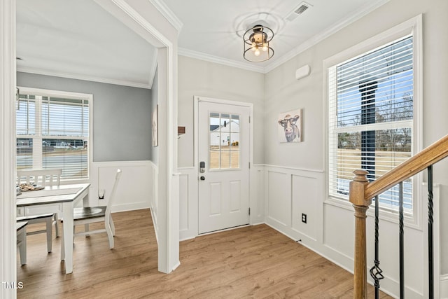 foyer with ornamental molding and light hardwood / wood-style floors