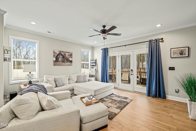 living room featuring ornamental molding, a wealth of natural light, and light hardwood / wood-style floors