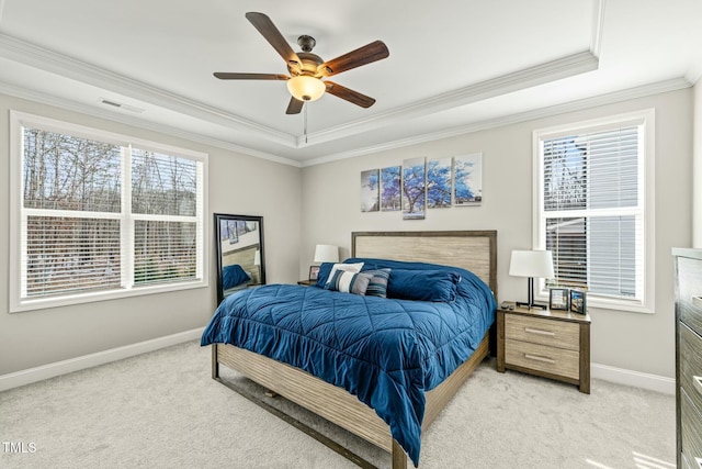 bedroom featuring a raised ceiling, ornamental molding, light colored carpet, and ceiling fan