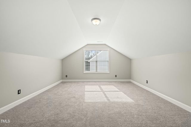 additional living space featuring lofted ceiling and light carpet