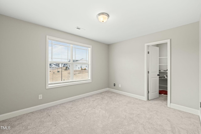 unfurnished bedroom with light colored carpet, a spacious closet, and a closet