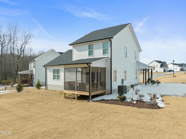 back of house with a sunroom and a lawn