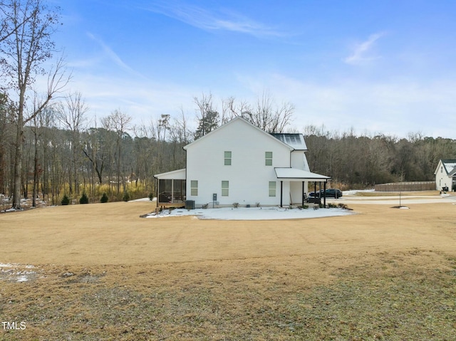 rear view of property featuring a sunroom and a lawn