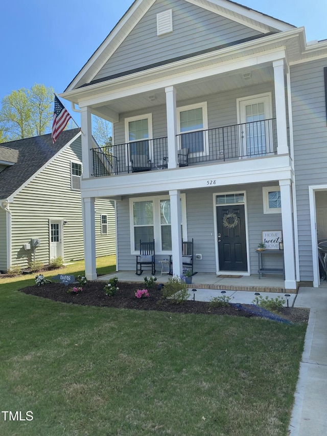 neoclassical / greek revival house with a balcony, covered porch, and a front lawn