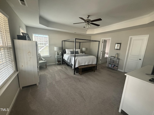 bedroom with ceiling fan, a tray ceiling, and dark carpet