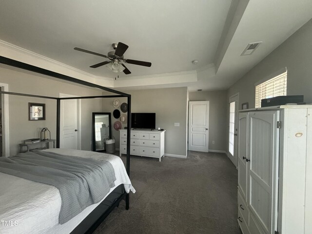 bedroom featuring a raised ceiling, dark colored carpet, crown molding, and multiple windows