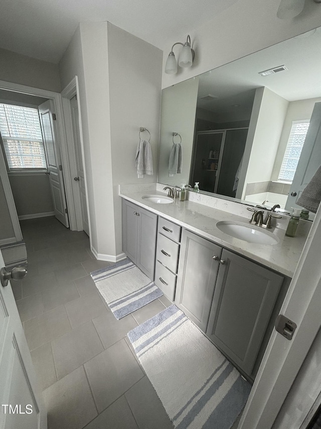 bathroom featuring a healthy amount of sunlight, tile patterned flooring, a shower with door, and vanity