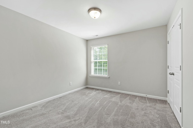 carpeted empty room featuring baseboards and visible vents