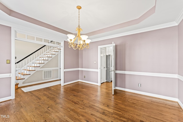 unfurnished room with visible vents, a tray ceiling, wood finished floors, stairway, and baseboards