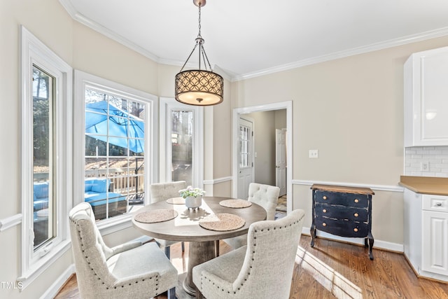 dining area featuring crown molding, light wood-style floors, and baseboards