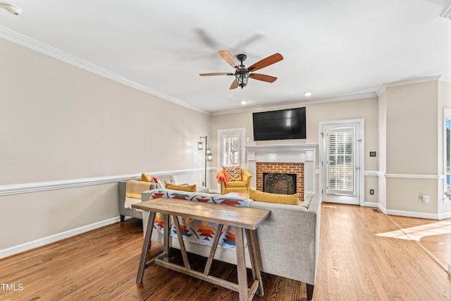 living area with a healthy amount of sunlight, crown molding, baseboards, and wood finished floors