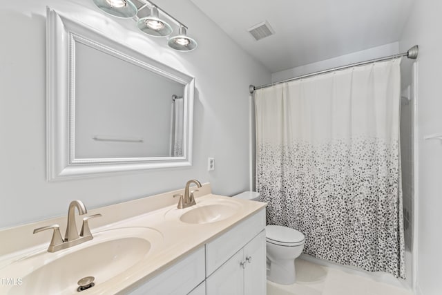 bathroom featuring double vanity, visible vents, toilet, and a sink