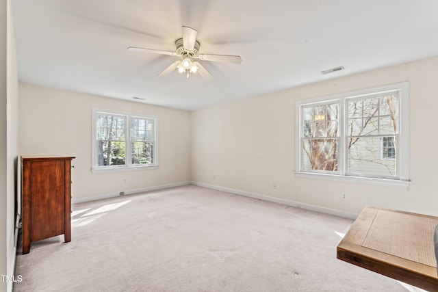 empty room with visible vents, light colored carpet, baseboards, and ceiling fan