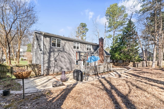 rear view of house with a patio, a gate, fence, a wooden deck, and a chimney