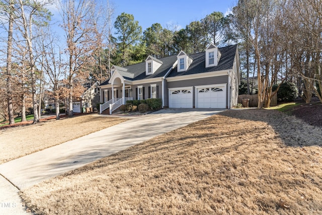 cape cod house with covered porch, concrete driveway, and a garage