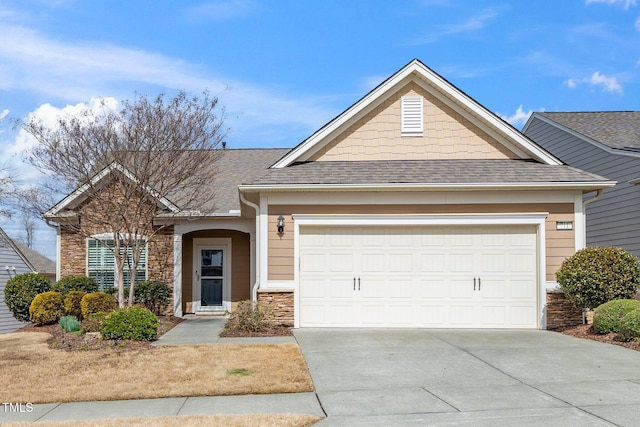 view of front of house featuring stone siding, concrete driveway, roof with shingles, and an attached garage