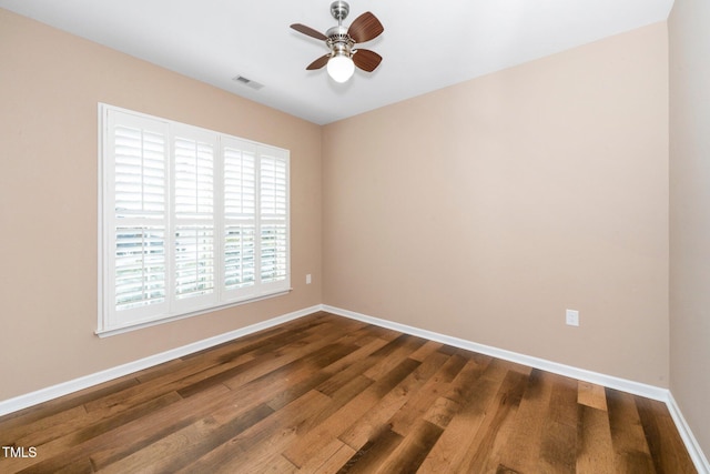 empty room with dark wood-style floors, baseboards, visible vents, and a ceiling fan