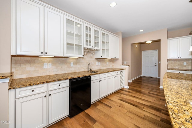 kitchen with light wood-style floors, white cabinets, a sink, light stone countertops, and baseboards